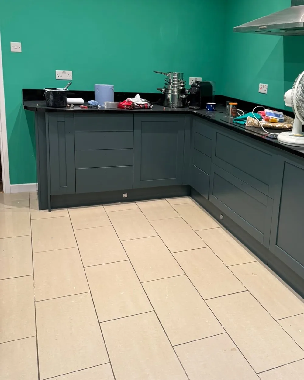 Kitchen corner run of base units resprayed in dark grey against a green wall